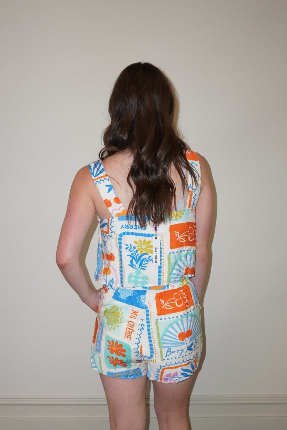 Person wearing a colorful patterned set standing against a plain wall.