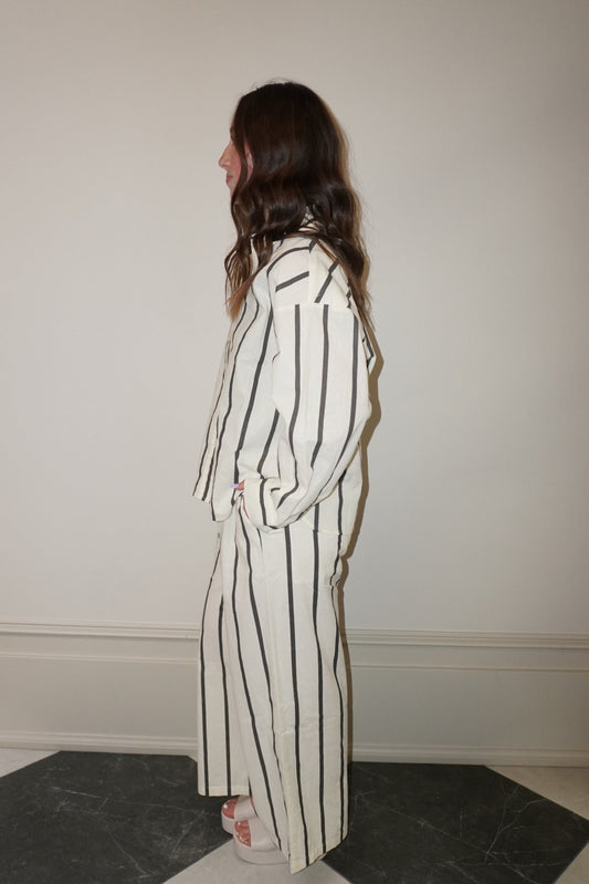 Woman wearing a striped suit standing in a room with a checkered floor.