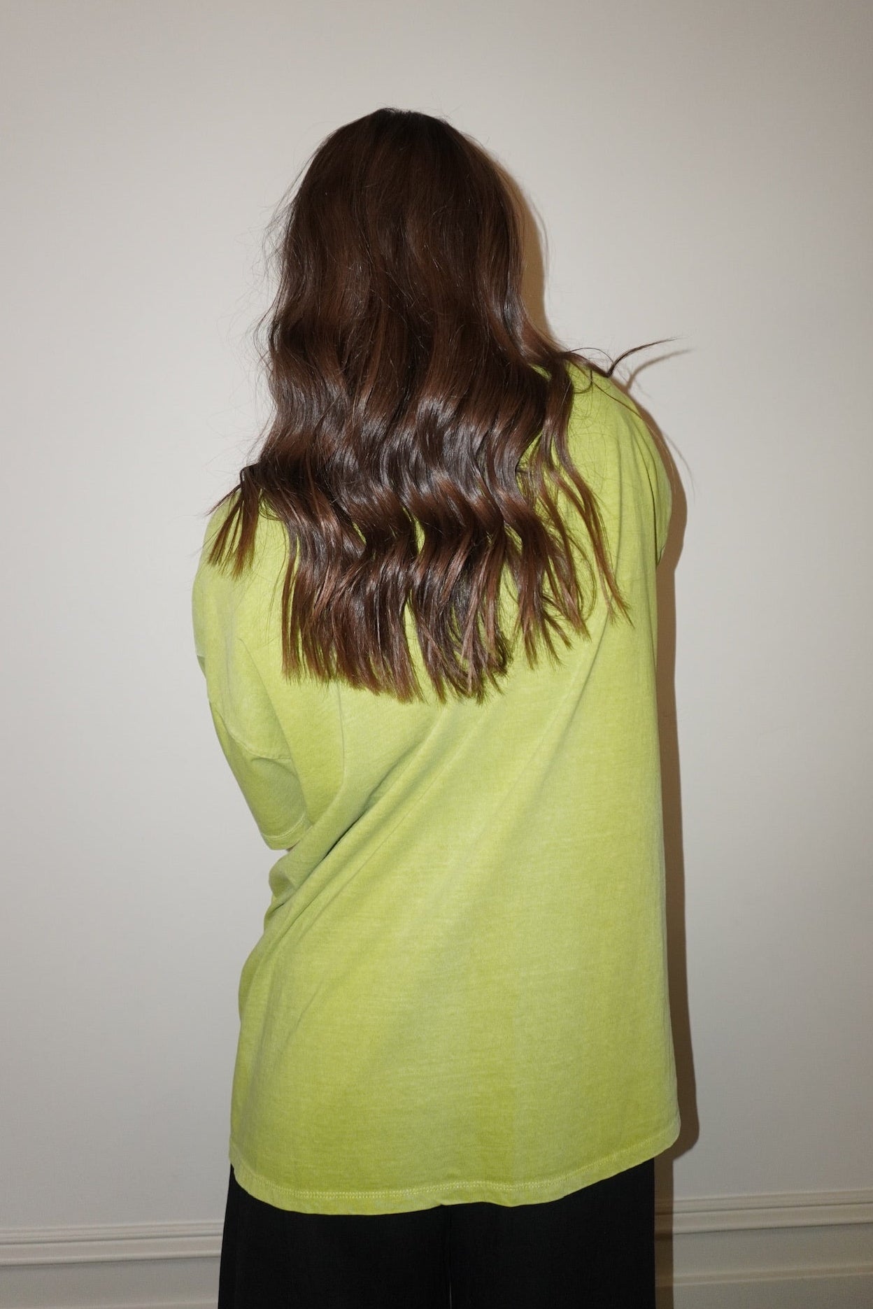 Person wearing a bright green t-shirt against a plain background
