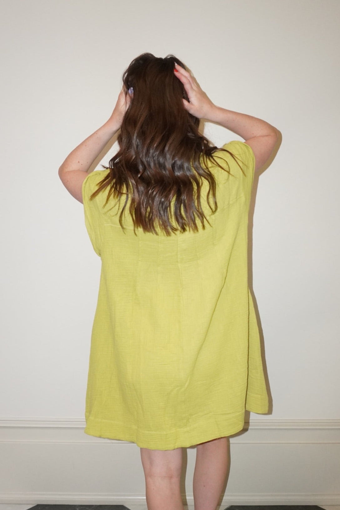 Person wearing a yellow dress standing in a room with a checkered floor.