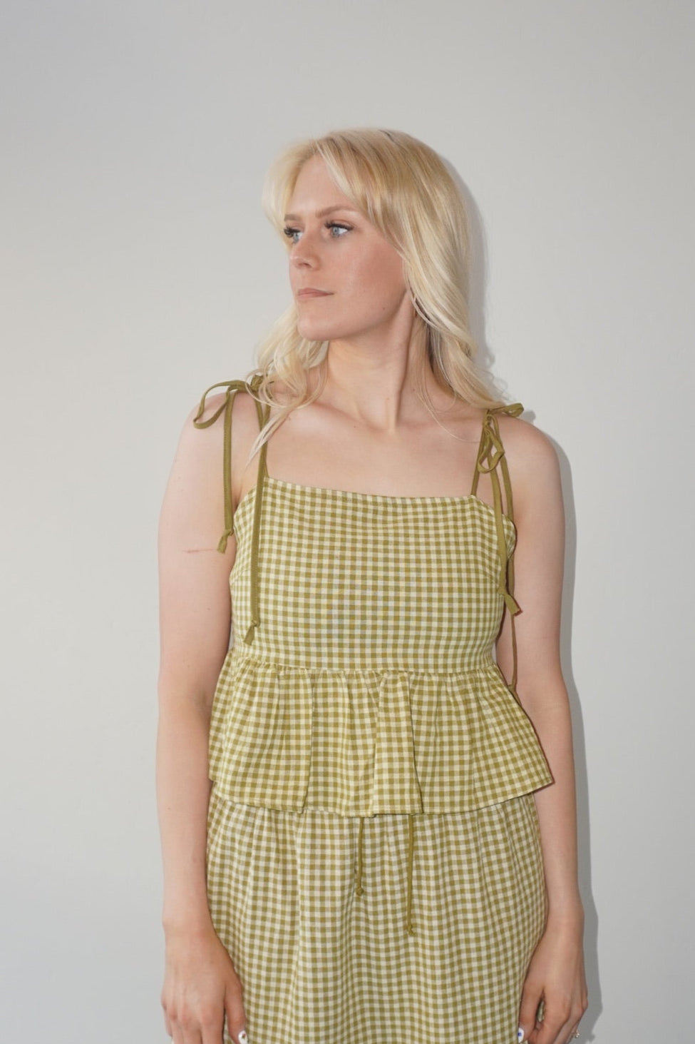 Woman wearing a yellow checkered set against a plain background