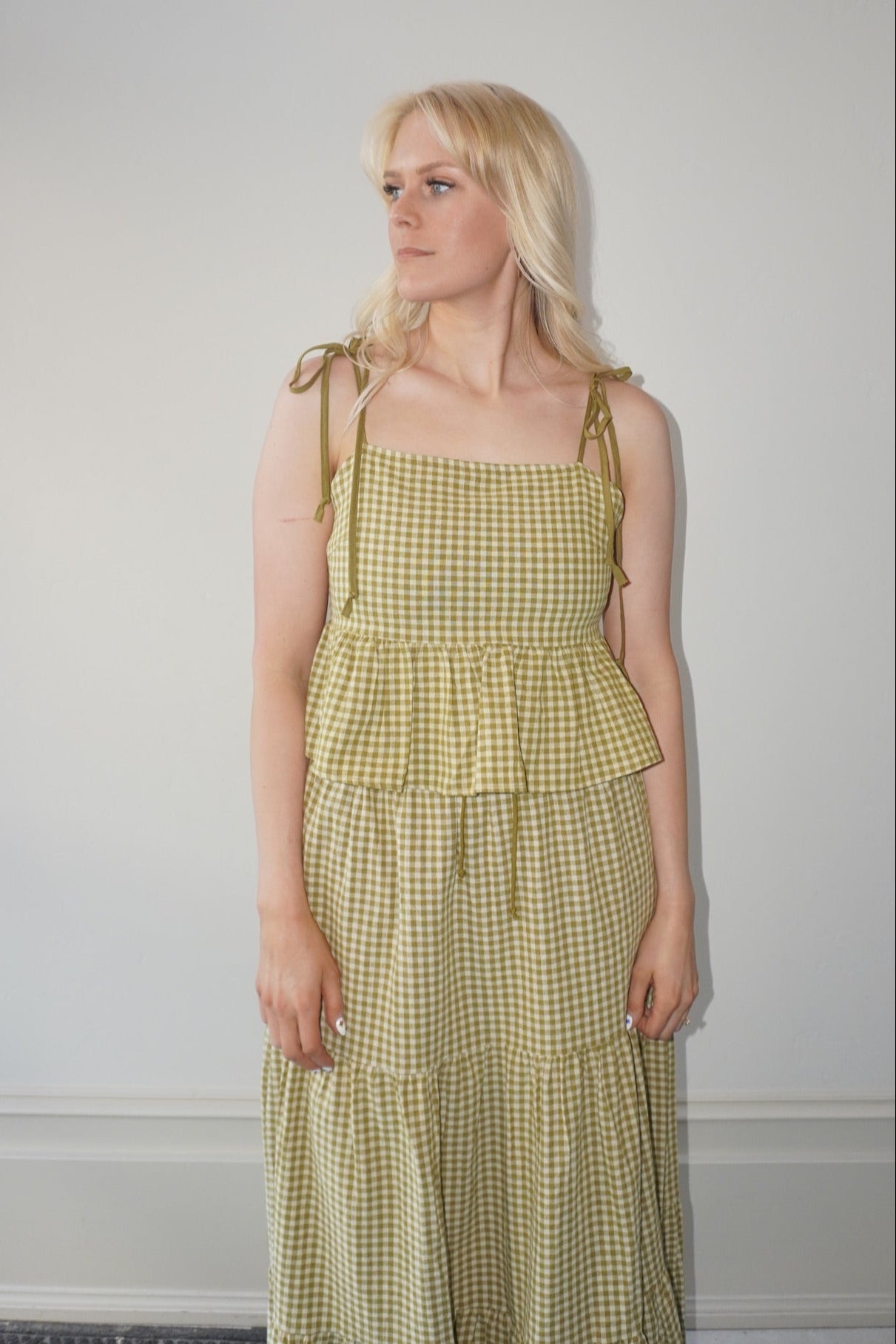 Woman wearing a yellow checkered set against a plain background