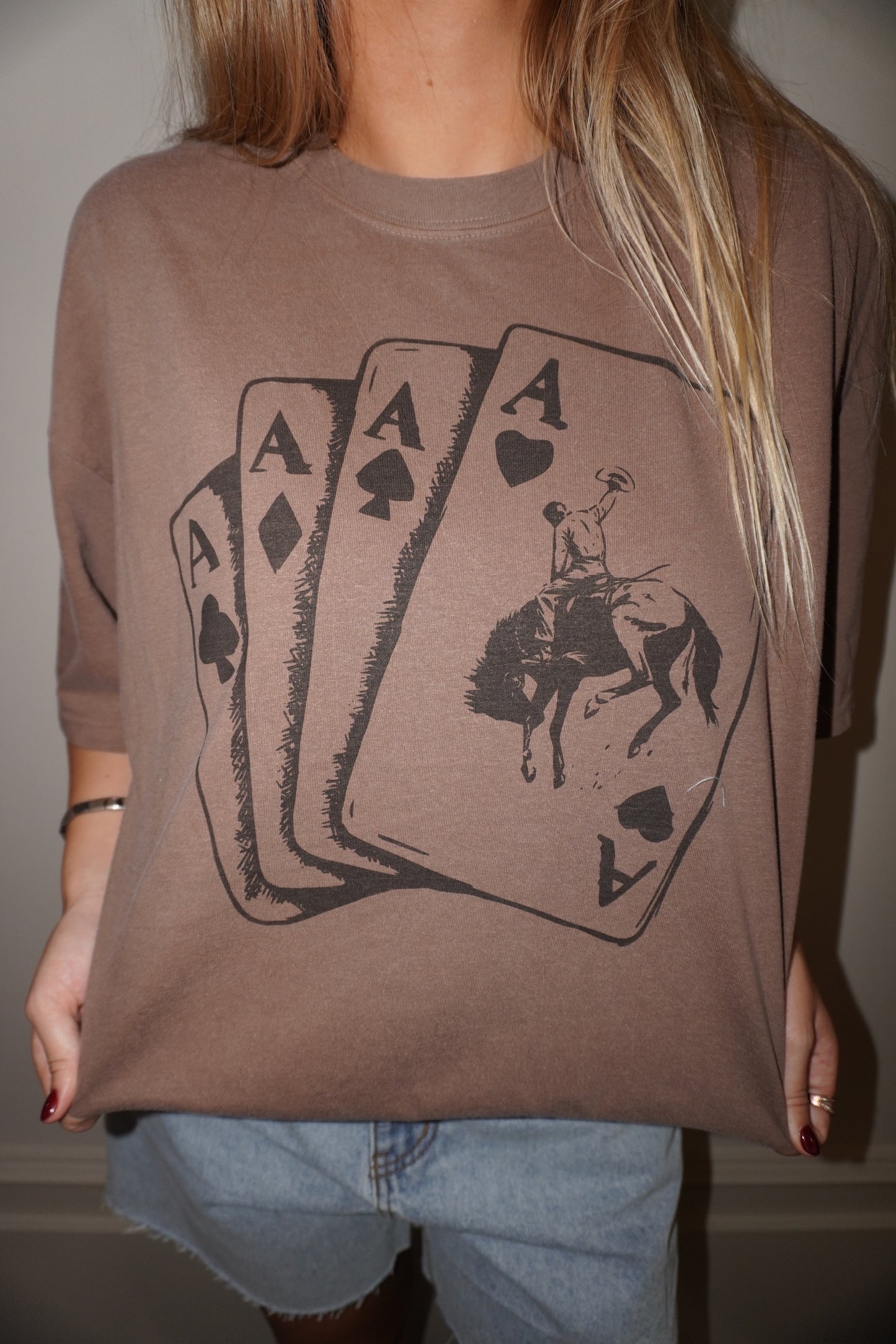 Person wearing a brown t-shirt with playing card design and horse illustration.