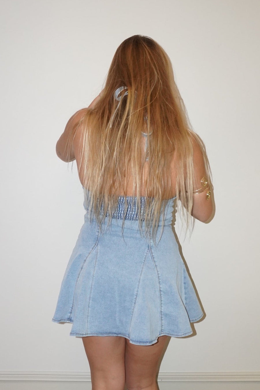 Person wearing a light blue dress standing against a plain white wall.