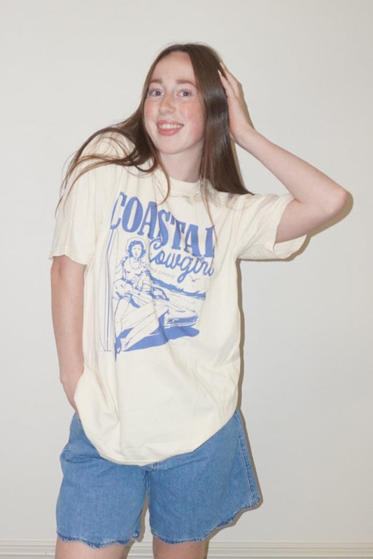 Person wearing a graphic t-shirt and shorts standing on a checkered floor.