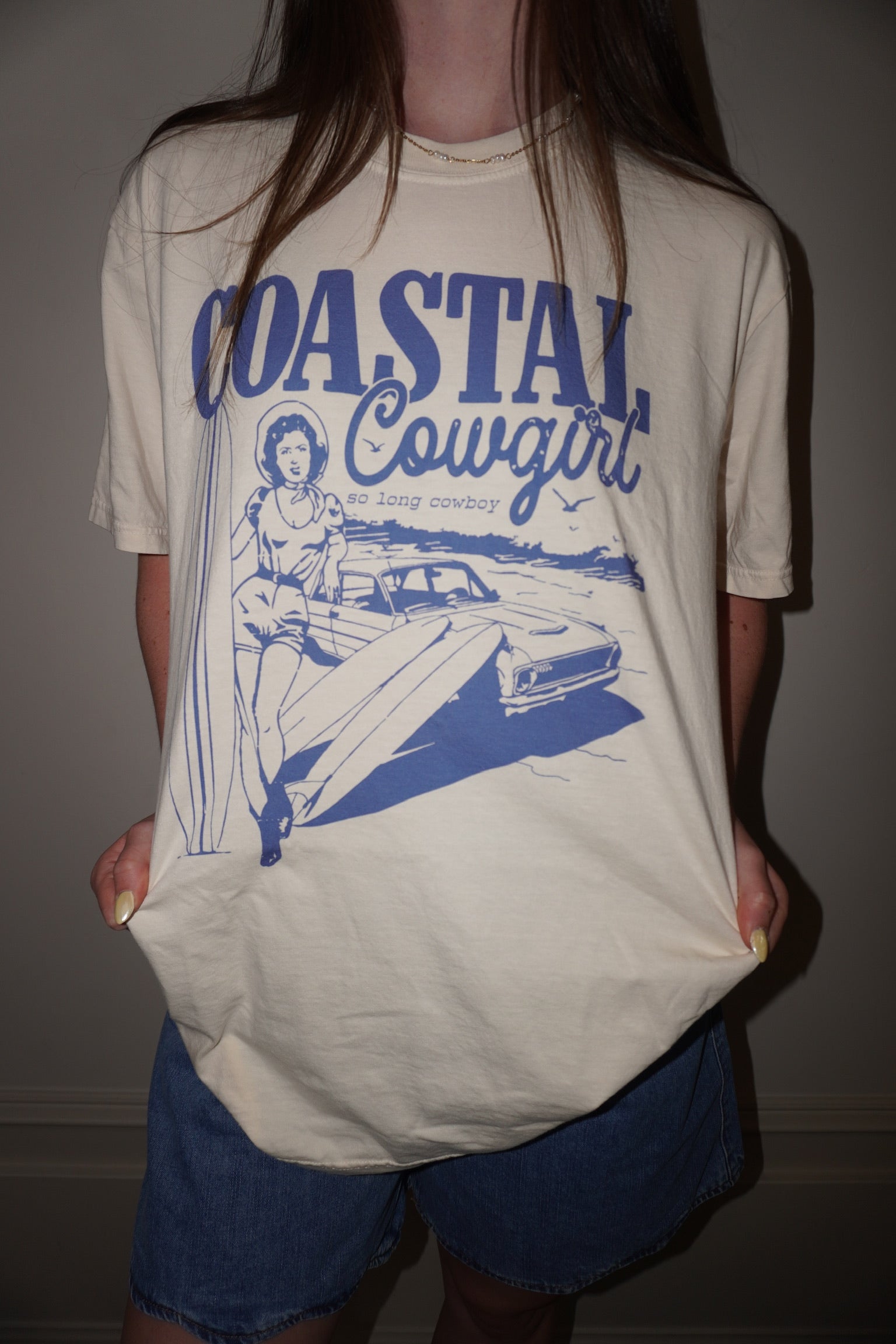 Person wearing a 'Coastal Cowgirl' t-shirt with a graphic design.