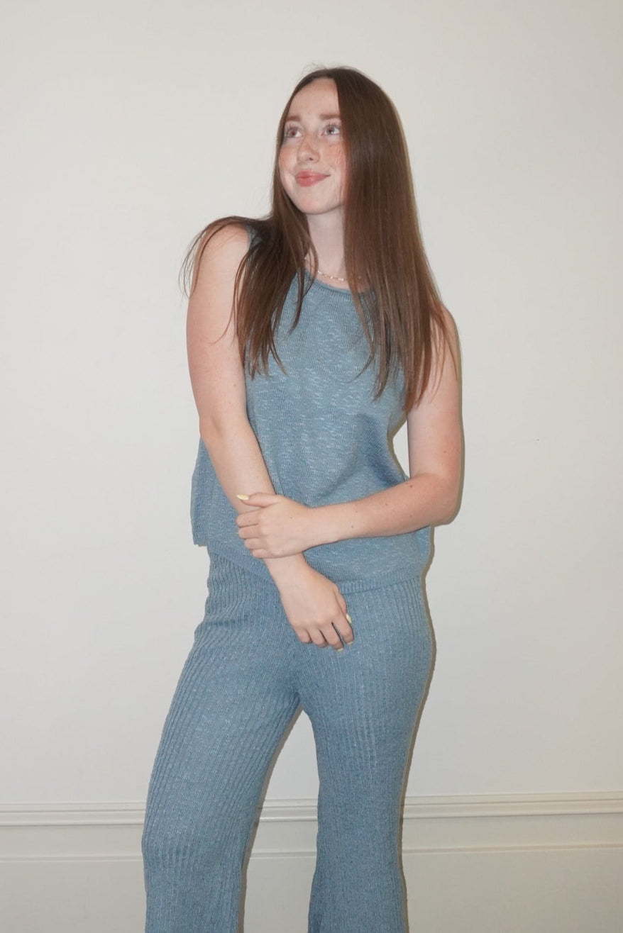 Woman wearing a blue set standing in a room with a checkered floor.