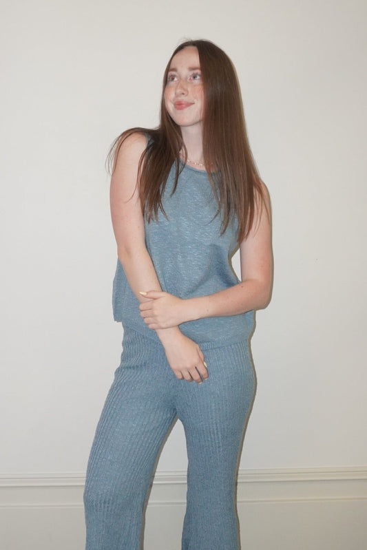 Woman wearing a blue set standing in a room with a checkered floor.