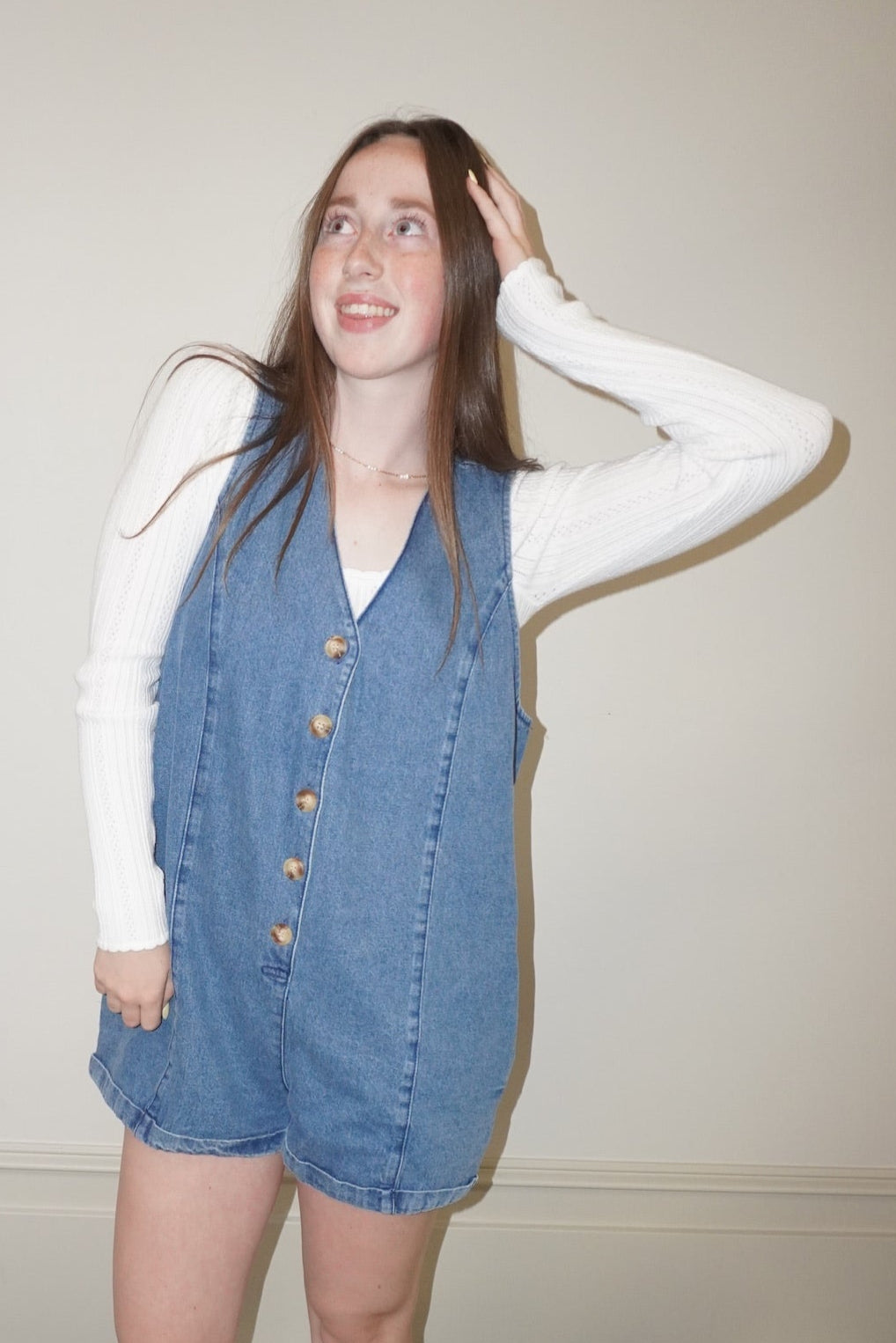 Person wearing a denim romper on a checkered floor.