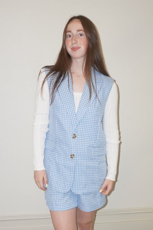 Person wearing a blue checkered outfit with a white shirt and yellow shoes on a checkered floor.