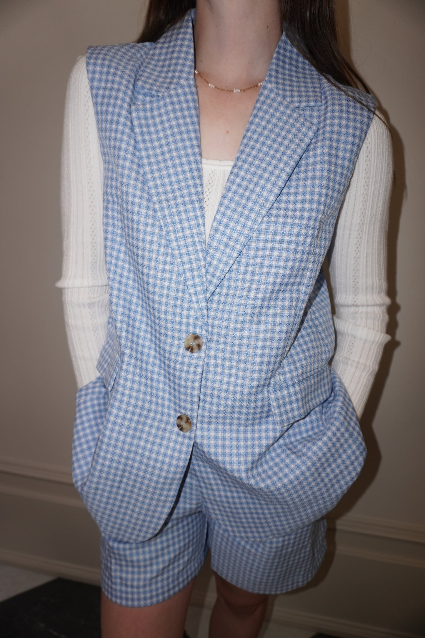 Mannequin wearing a blue checkered vest and shorts set against a neutral background