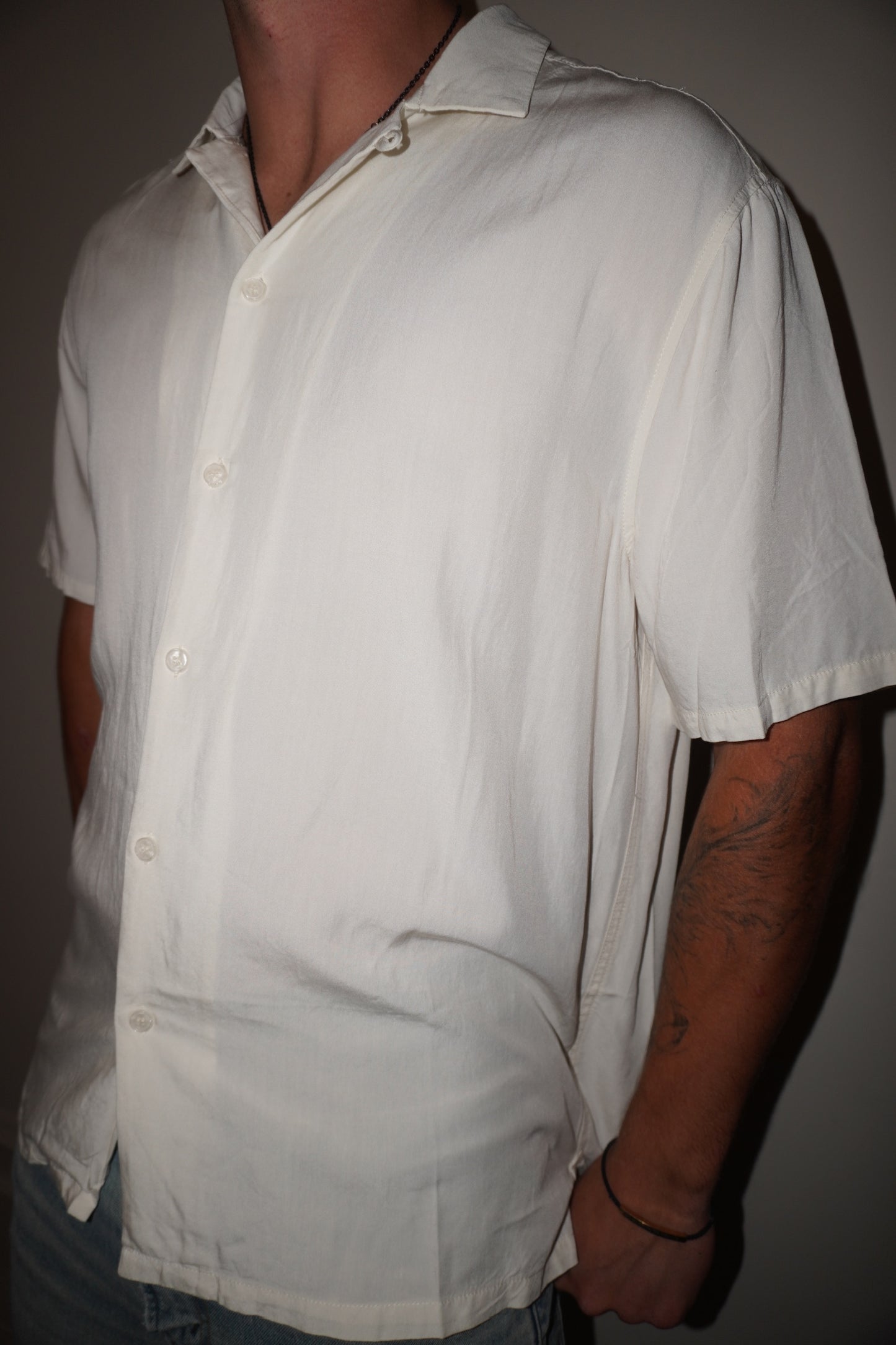 Man wearing a light-colored short-sleeve shirt against a plain background