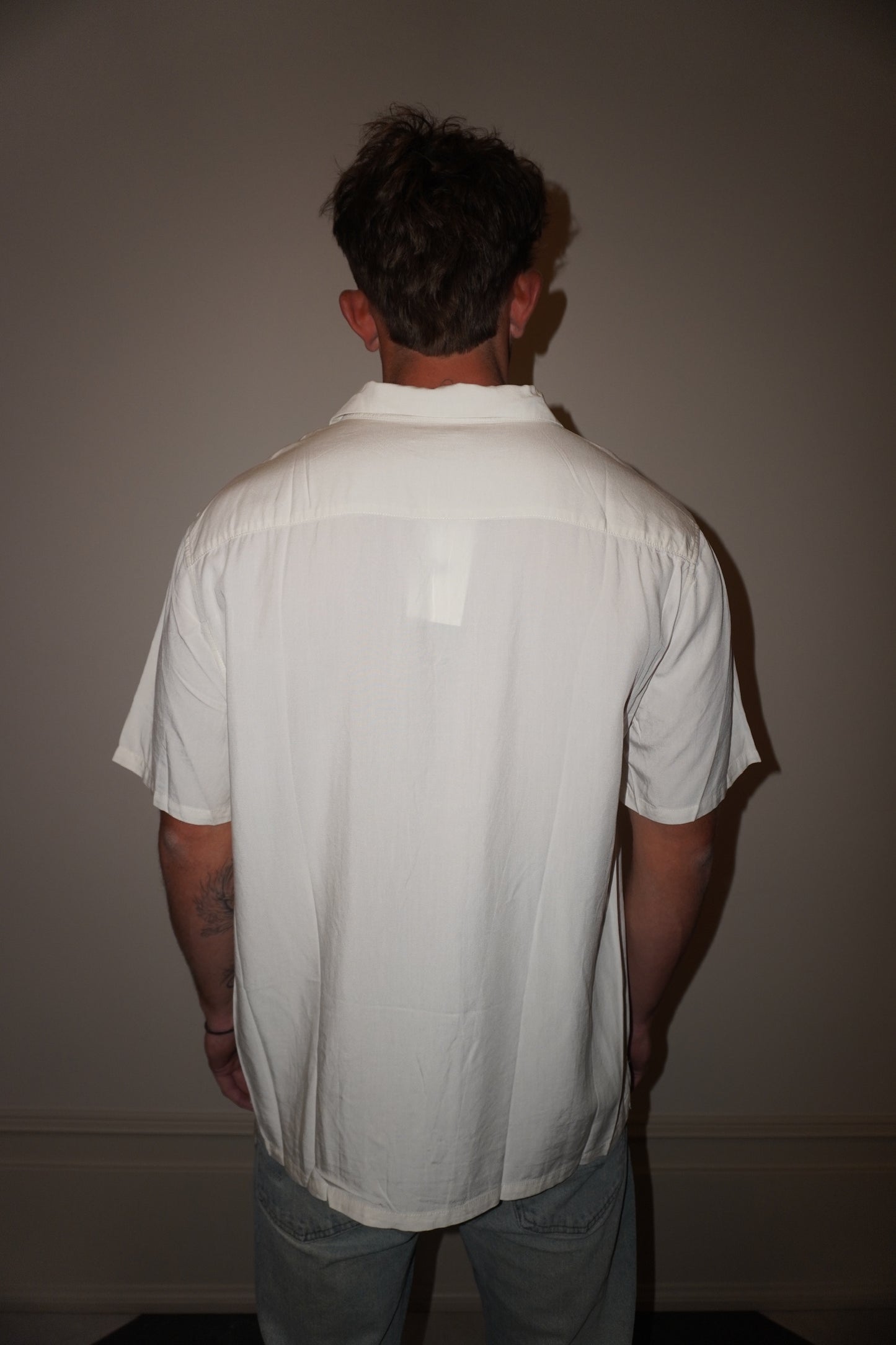 Person wearing a white shirt with a visible tag against a plain background