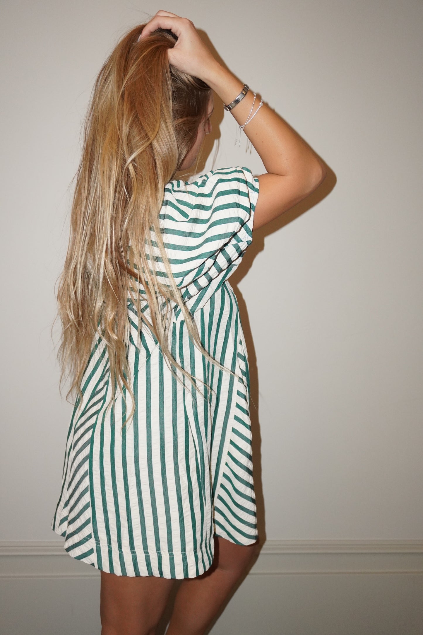 Person wearing a green and white striped romper against a plain background