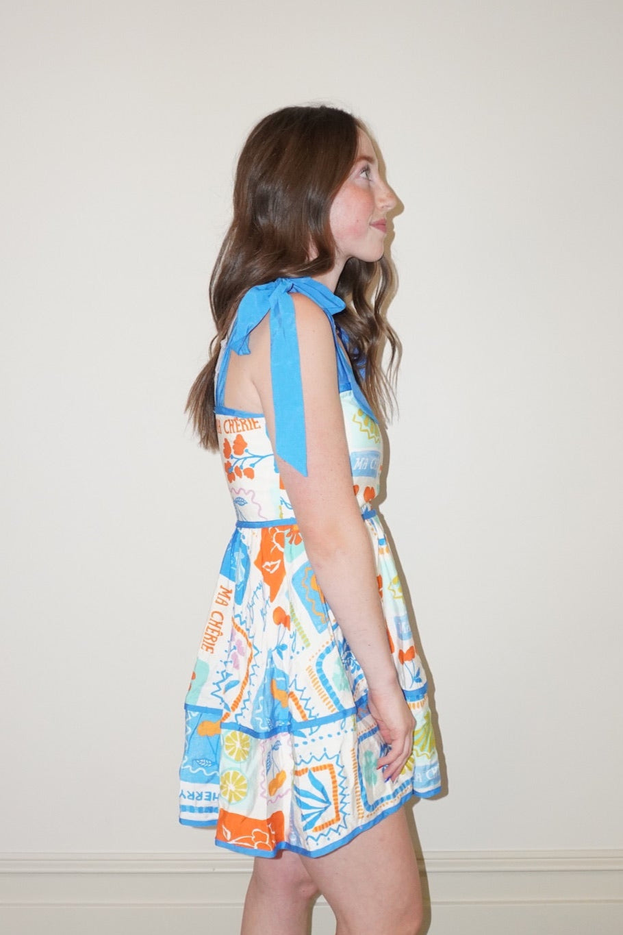 Woman wearing a colorful dress standing on a checkered floor.