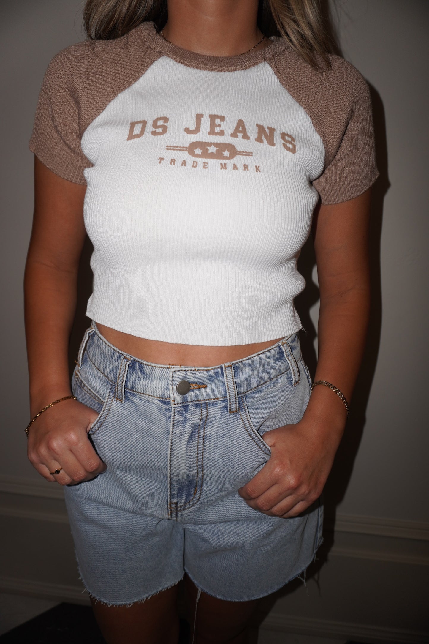 Person wearing a 'DS Jeans' crop top and denim shorts against a neutral background