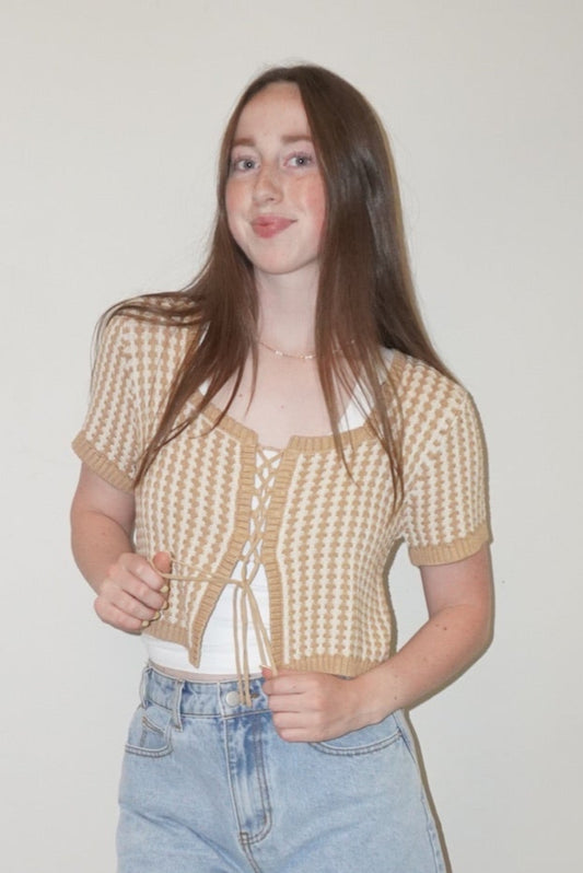 Person wearing a checkered shirt, denim shorts, and white shoes on a checkered floor.