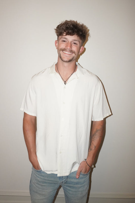 Man wearing a white shirt and blue jeans against a plain background